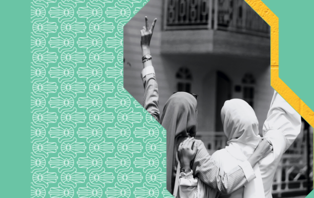 We see two women, wearing headscarves, from behind, who are embraced with their hands raised in a peace sign.